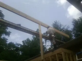 Carpenter setting a ridge beam over a new addition frame — Ice Dam Removal by Roofing Brothers in Wadesville