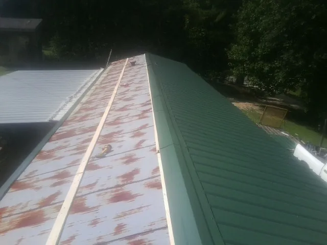 Old rusted panels beside newly installed green metal roofing — Wind Damage Roof Repair by Roofing Brothers in Wadesville