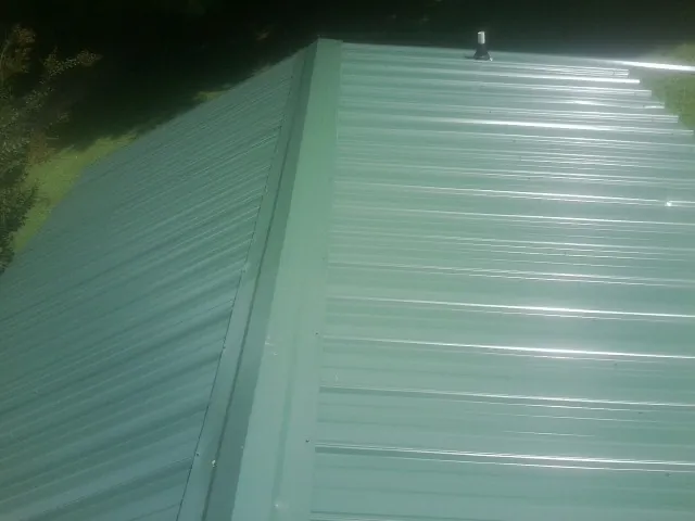 New green metal panels meeting at the ridge of a roof — Flat Roof Repair work by our crew in Wadesville