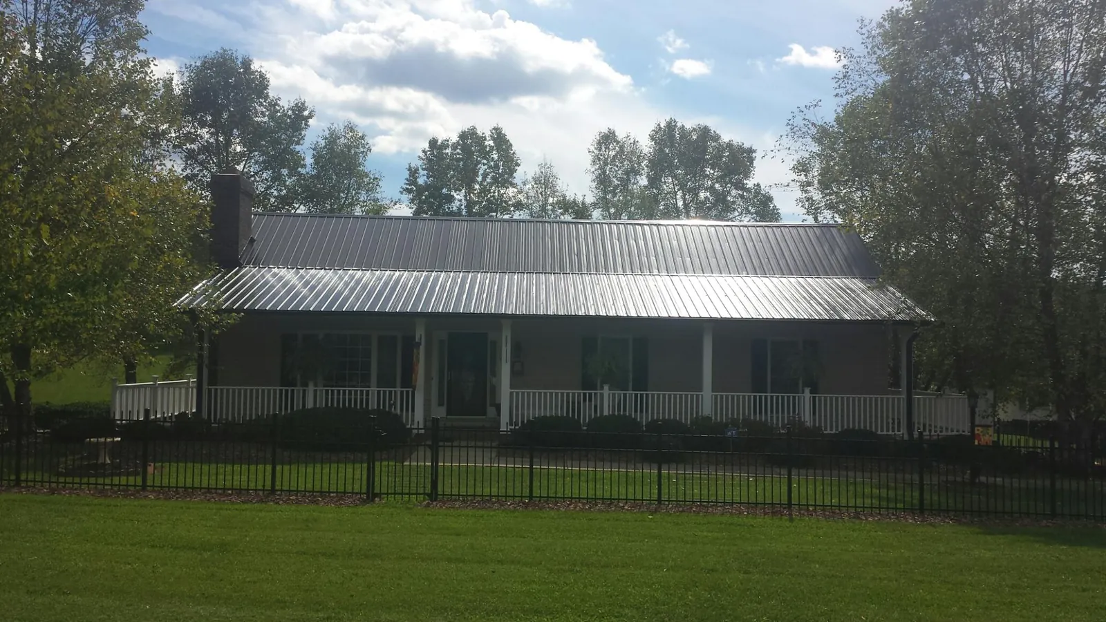 Gray metal roof on a brick ranch with a full width front porch — Gutter Guard Installation work by our crew in Wadesville