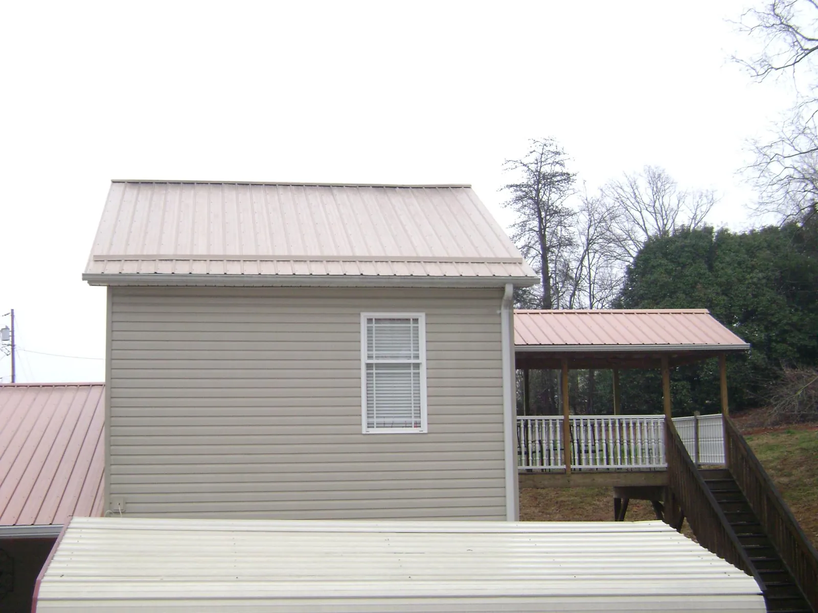 Tan metal roofs on a two story addition and attached porch, from a Roof Replacement job in Wadesville