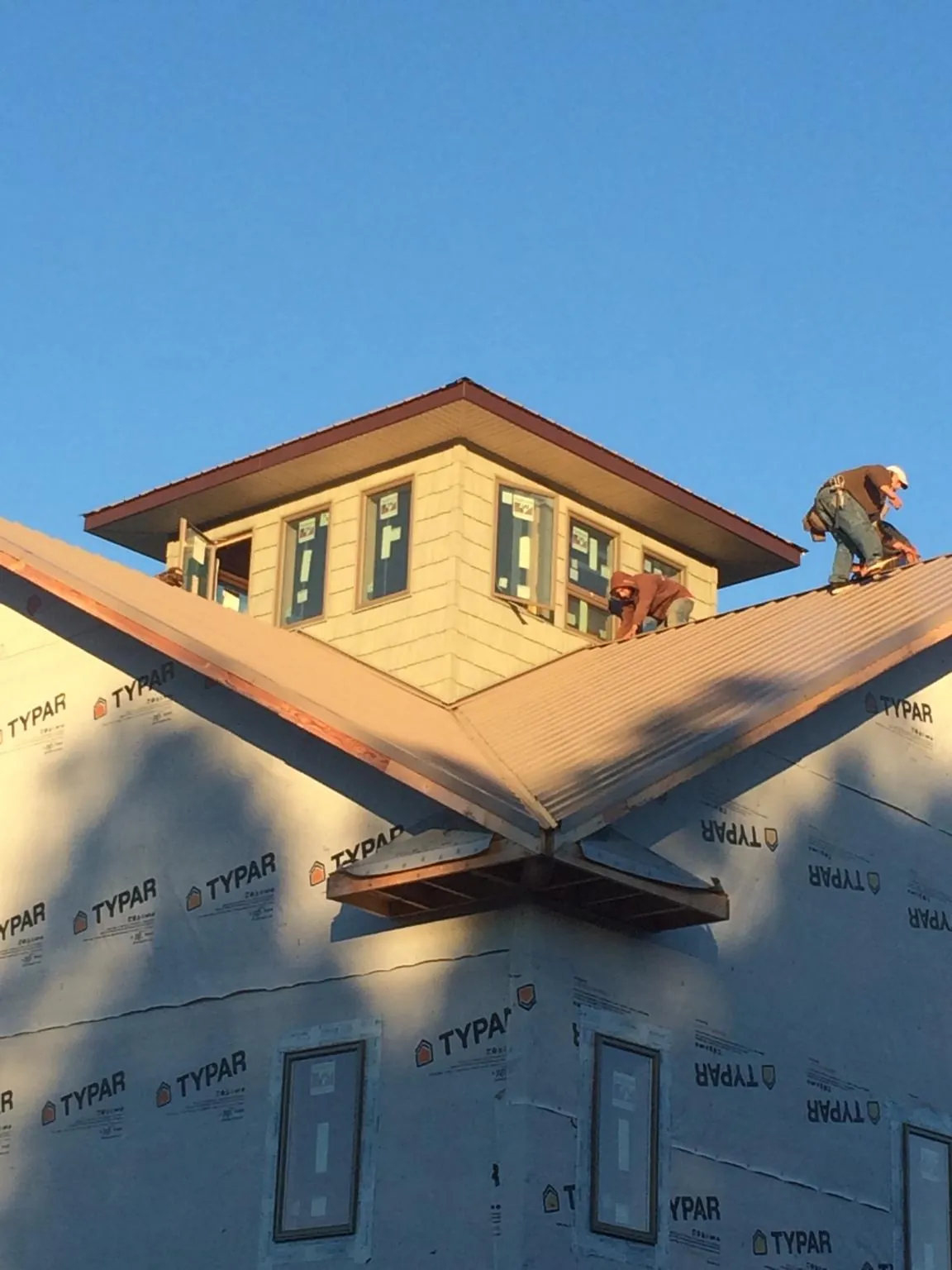 Roofers working around a rooftop cupola on a new metal roof at sunset — Roof Waterproofing in Wadesville by Roofing Brothers